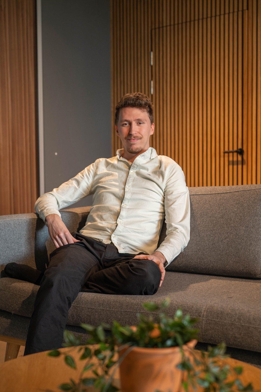 Entreprenören Philip Alm som är VD på startupen VISS.AI sitter i en grå soffa. 
