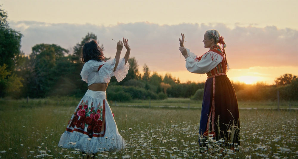 Två kvinnor som dansar på ett fält av prästkragar.