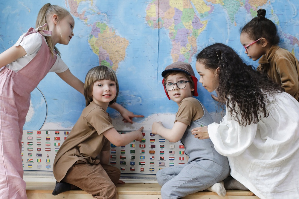 Barn med olika etnicitet som pekar på en världskarta.