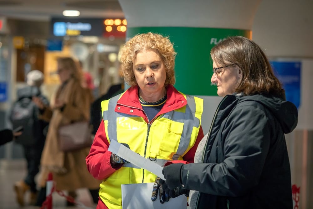 Kvinna i reflexväst ger ett informationsblad till en annan kvinna.