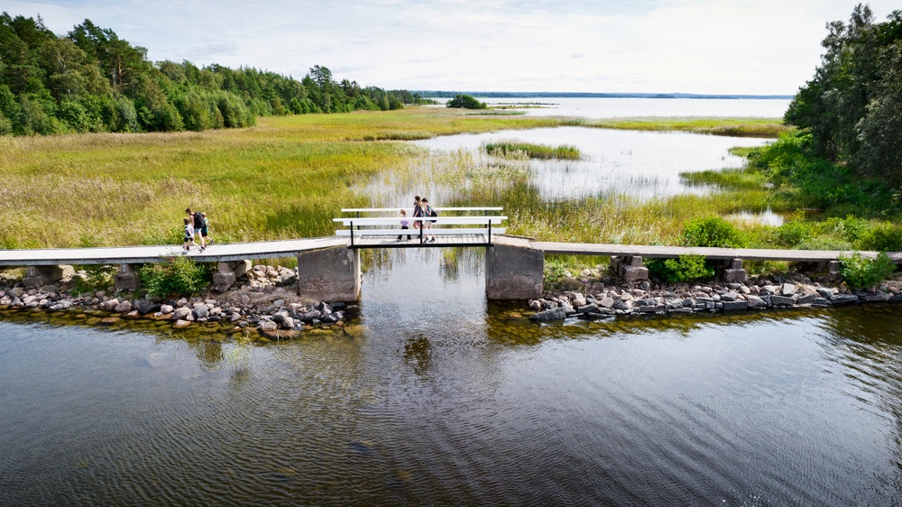 En familj går över en liten bro som går mellan öarna i Kristinehamns skärgård.