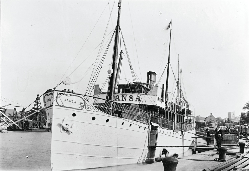 En svartvit bild på en gotlandsbåt, som fotograferats runt 1900-talets början. Båten ligger vid kaj i Visby. 