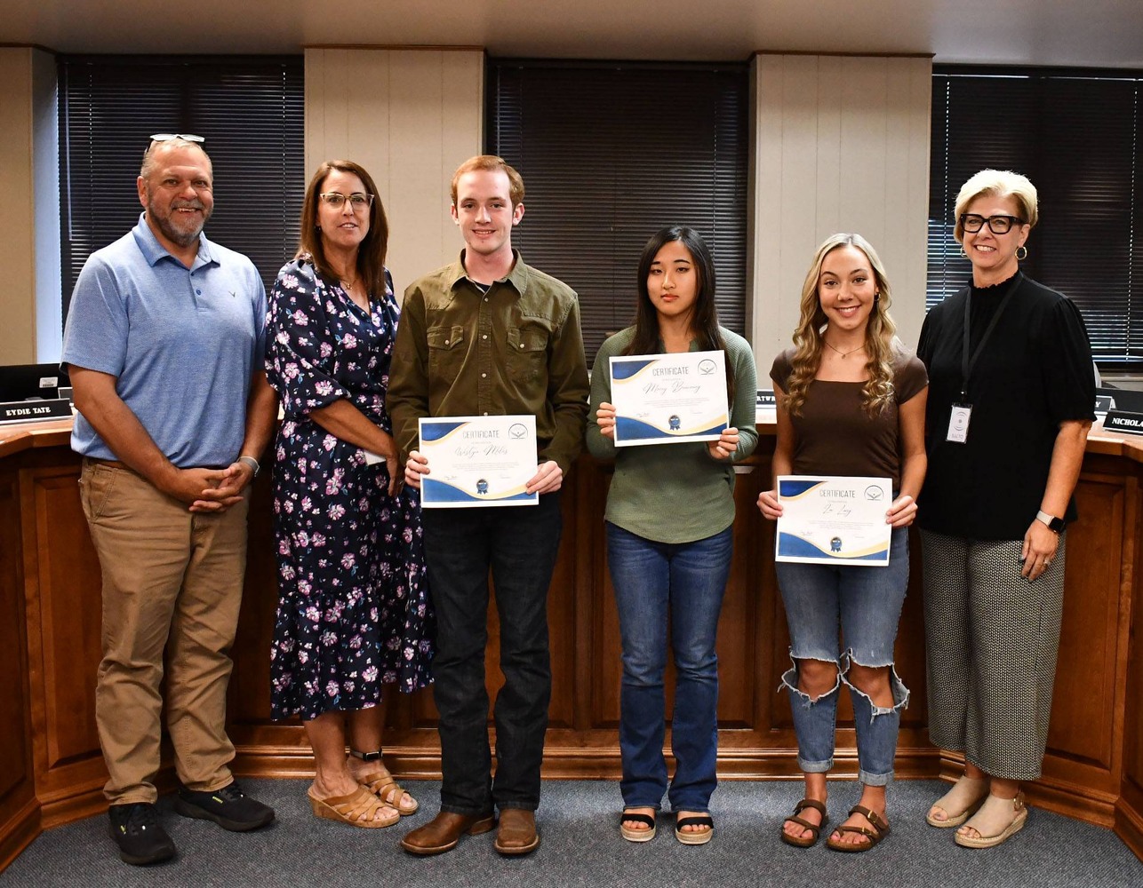 6 people pose for photo, with 3 holding certificates