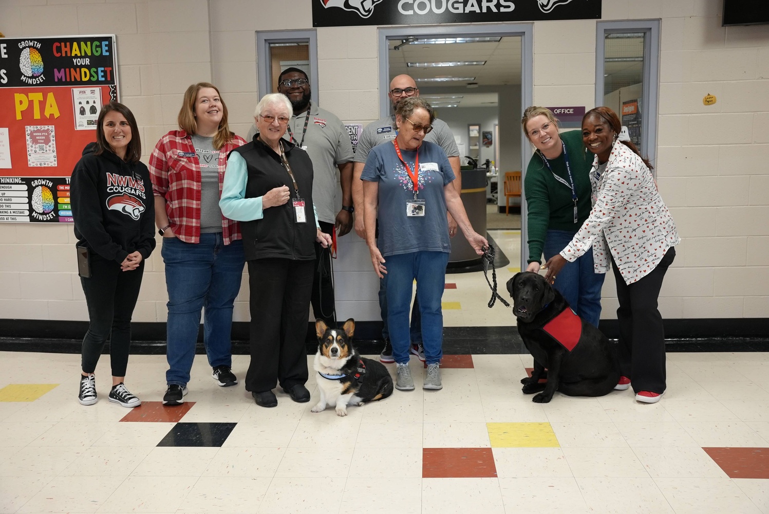 two therapy dogs post with their owners and staff members at nwms