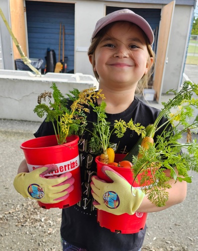 Student holding two buckets full of harvested vegetables