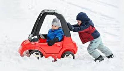 Child pushing toy car through snow