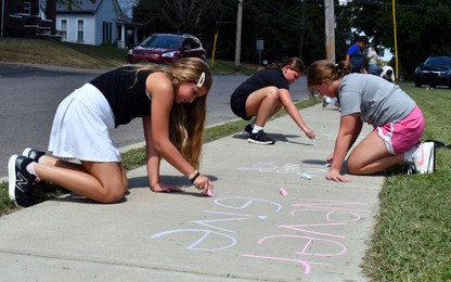 3 people draw on sidewalk with chalk