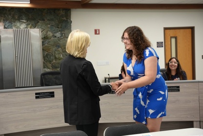 school board president lynn goebel shakes the hand of allena locklear after swearing her in at school board meeting