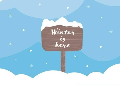 A wooden sign with snow on top reads 'Winter is here' against a blue sky with snowflakes.