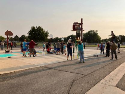 Several adults and children making repairs on a school playground