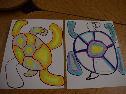 2 turtle drawings in the style of Indigenous artist Norval Morrisseau. The turtle on the left is yellow and orange, and the turtle on the right is blue and purple.