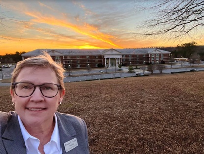 Donna Burke in front of Bumpus Middle School at sunset.