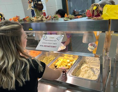 1 person gets corn from cafeteria tray