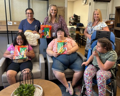 3 students and 3 school staff members pose for a photo holding supplies for the new resource center