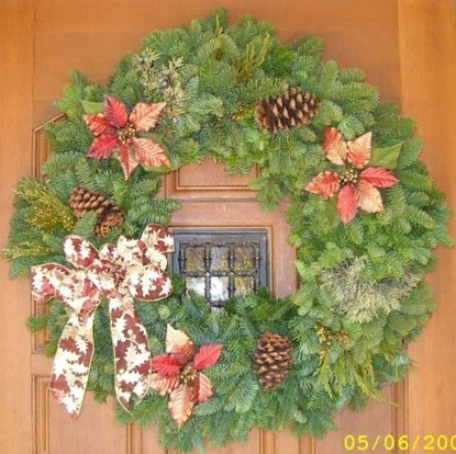 Decorated wreath on a door with bow, pine cones, and poinsettias