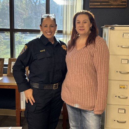 A woman in a pink sweater poses next to a woman in a dark blue CHP uniform.