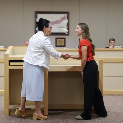 Board President Julia Burns shakes hands with student board member Mary Jane Gilliam