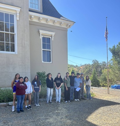 Students standing in front of LL community schoolhouse museum