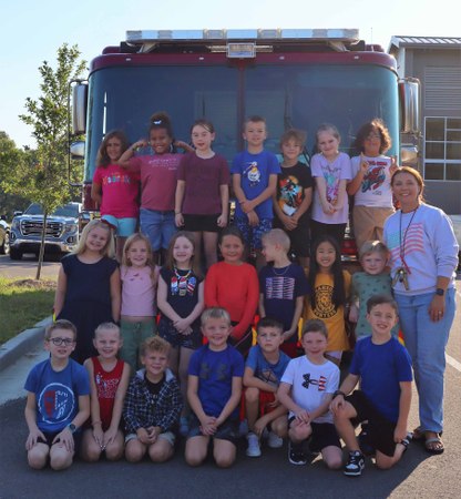 Class of about 20 people pose by fire truck