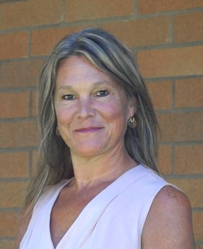 Superintendent Alison Brynelson smiling and standing in front of a brick wall