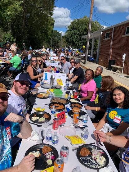 Aa group of people gathered around a table outside.