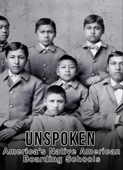 Historical black and white photo of native american children wearing suits at a boarding school