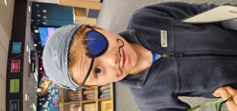 Student dressed as pirate wearing a head scarf and eye patch with a pencil mustache drawn over upper lip