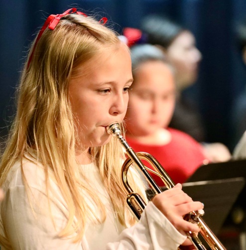 Students play musical instruments at the assembly