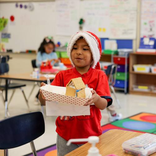 A boy holding a gingerbread house.