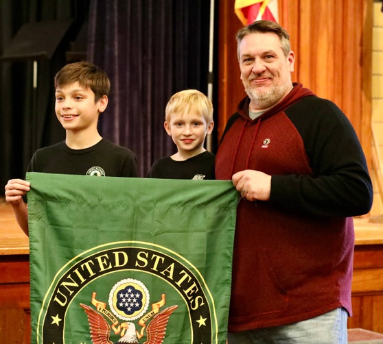 A veteran stands with students after the ceremony