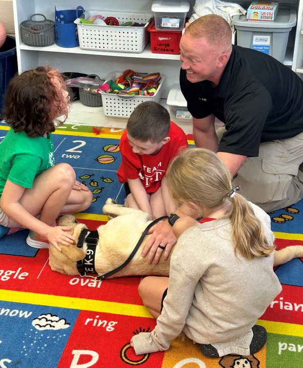 3 students and school resource officer with dog