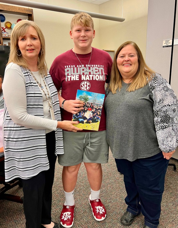 Picture of Tina Jowell presenting yearbook to Chantea and Riley Allen