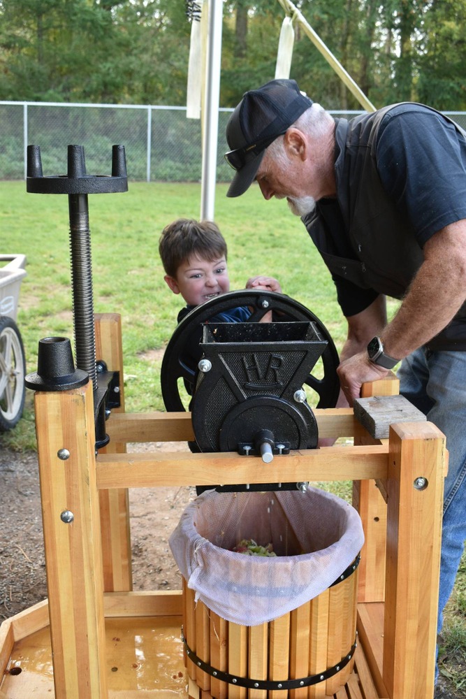 boy turning a cider press with all of his might