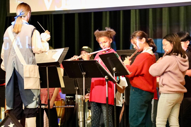 Students play musical instruments at the assembly