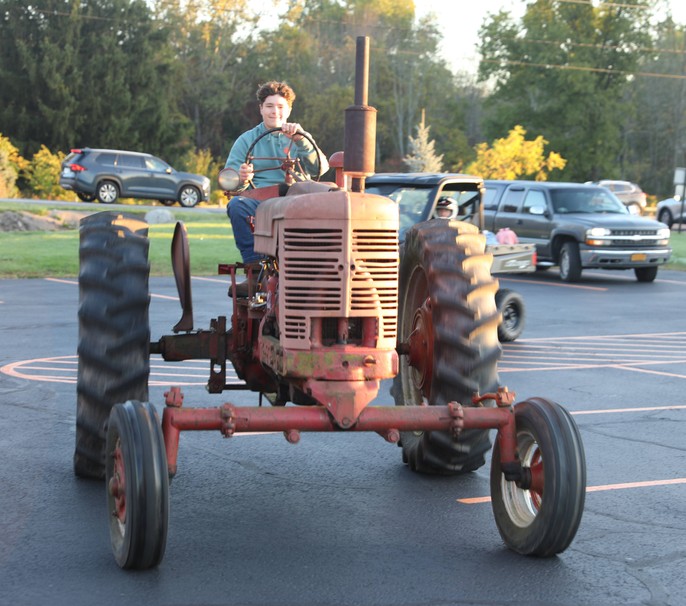 A student driving a tractor in the parking lot