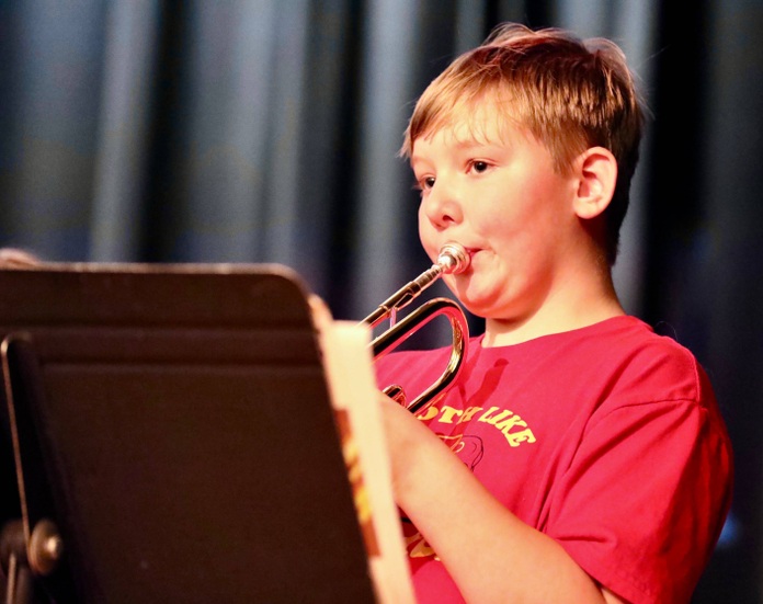 Students play musical instruments at the assembly