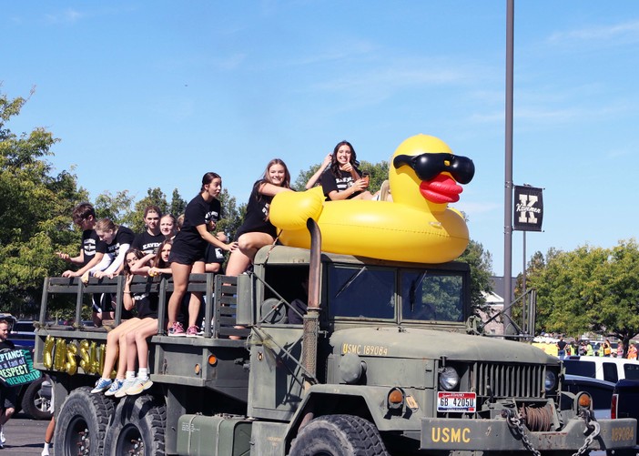 Swim team members riding on a truck with large rubber duck