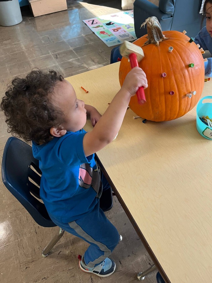 student hammering tee into pumpkin