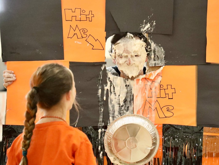 A staff member receives a pie to the face