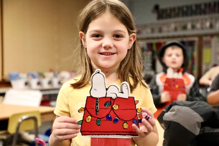 A student shows their Snoopy arts and crafts project.