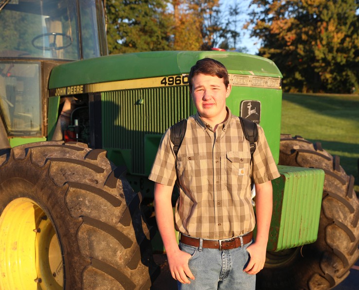 A student stands in front of a tractor