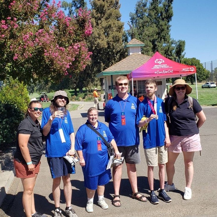 A group of students and adults pose for a photo at a golf course