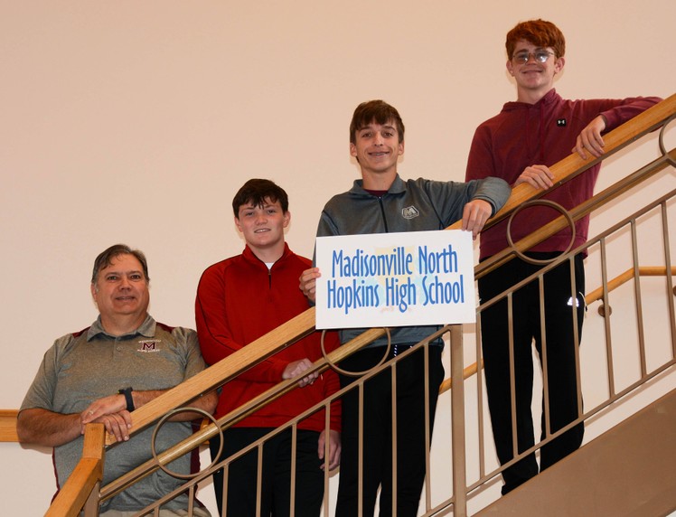 5 people stand on staircase with sign with the words Madisonville North Hopkins High School