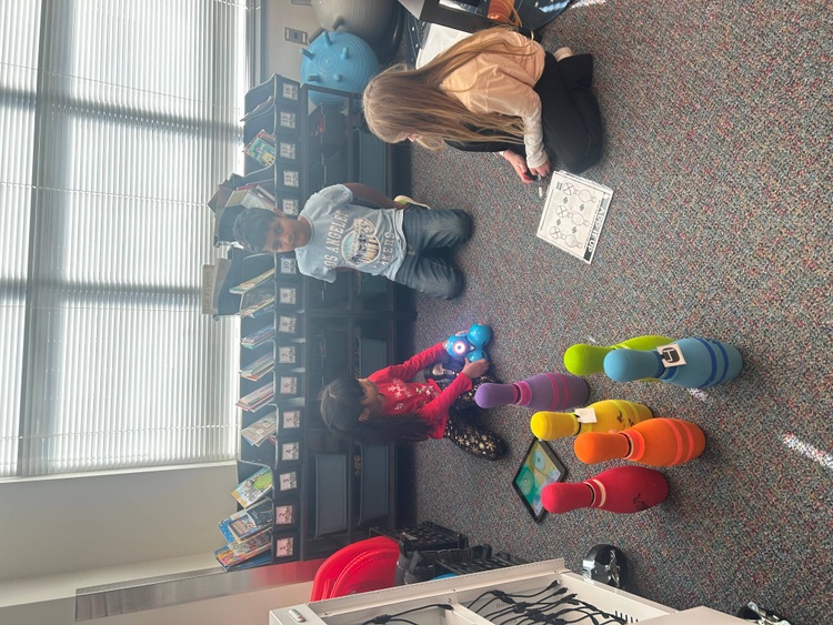 two students programing a robot to knock over bowling pins