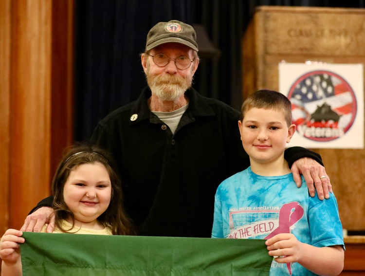 A veteran poses with students after the ceremony