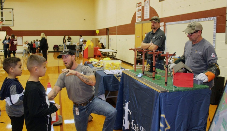 3 electrical workers talk to 2 kids with demonstration model on table