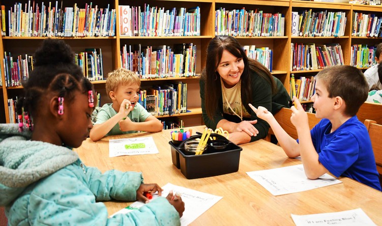 Adult talks to 3 kids seated at table