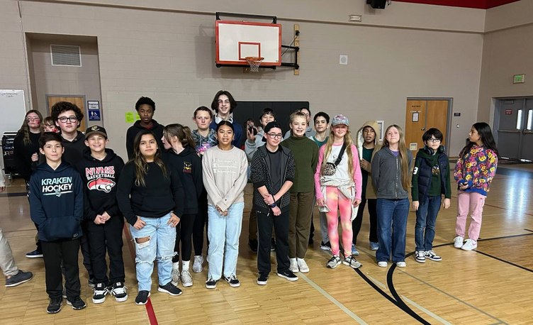 A group of students stand together in a gymnasium, smiling for the camera.