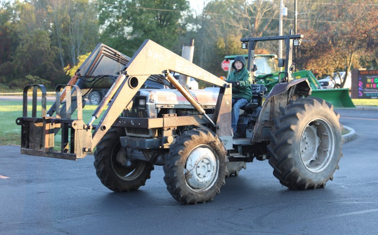 A student drives a tractor in the parking lot