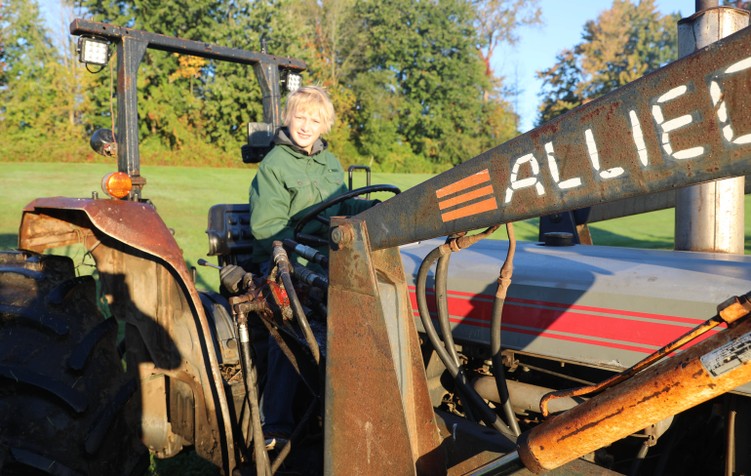 A student smiles while sitting on a tractor